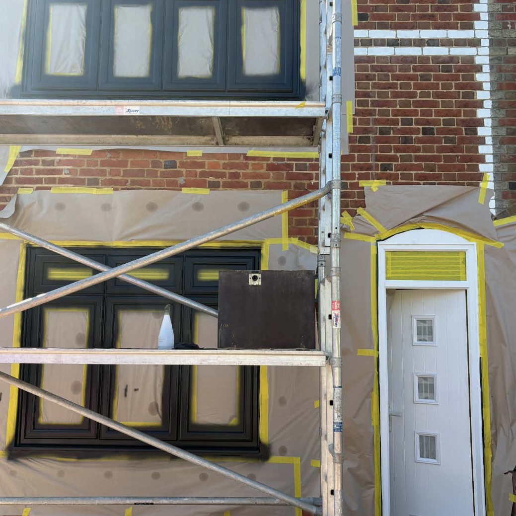 Scaffolded residential property with newly sprayed white UPVC front door